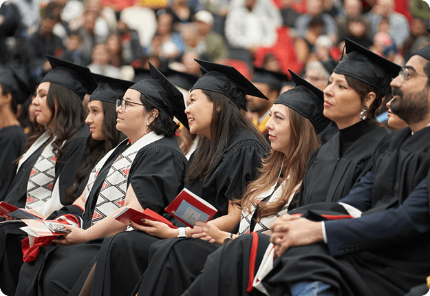 Students dressed in regalia watching the ceremony