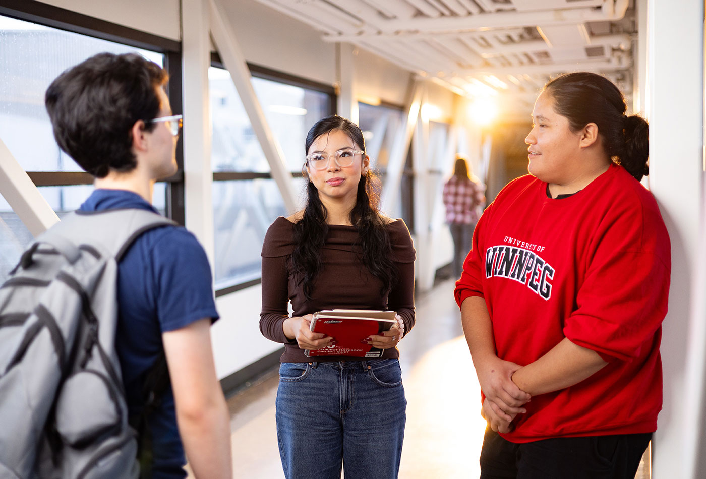 Three students standing in a hallway talking