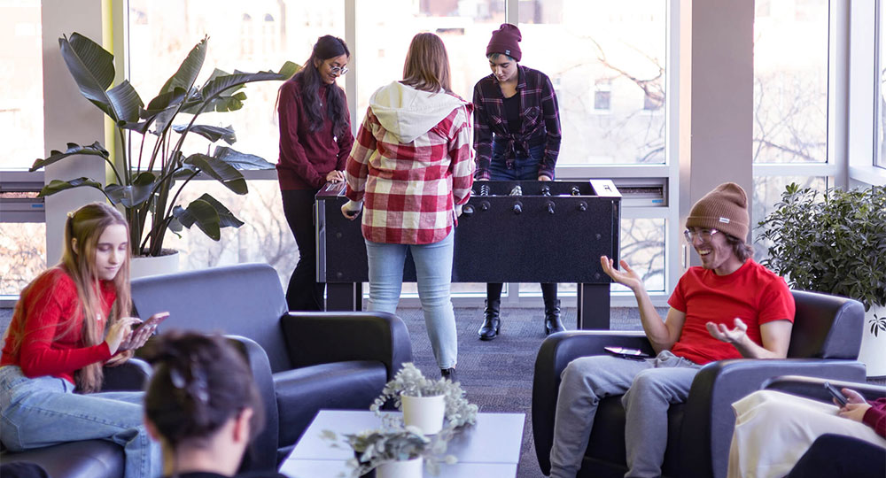 Students playing Foosball and relaxing in McFeetors Hall