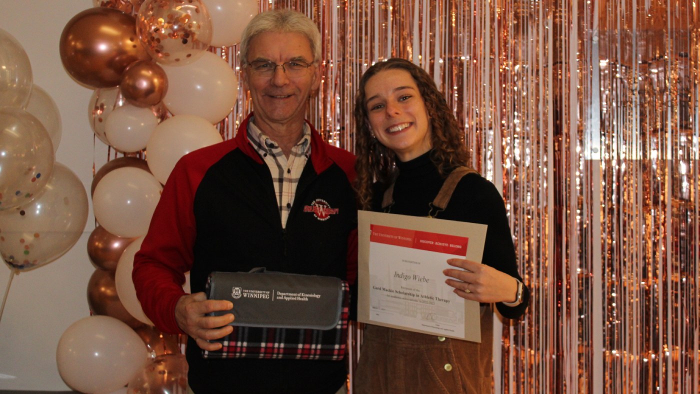 Student Indigo Wiebe stand with Gord Mackie Scholarship in Athletic Therapy