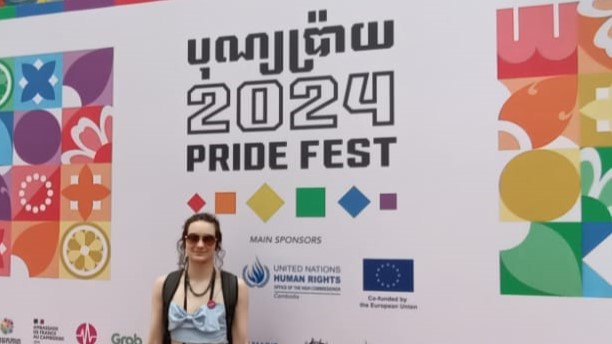 Daniko standing in front of a 2024 Pride Fest banner