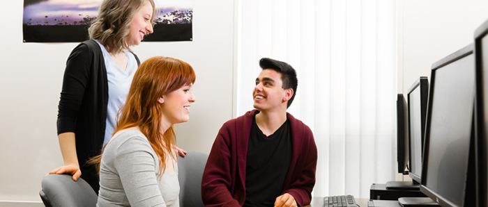 Three students discussing an essay on a computer