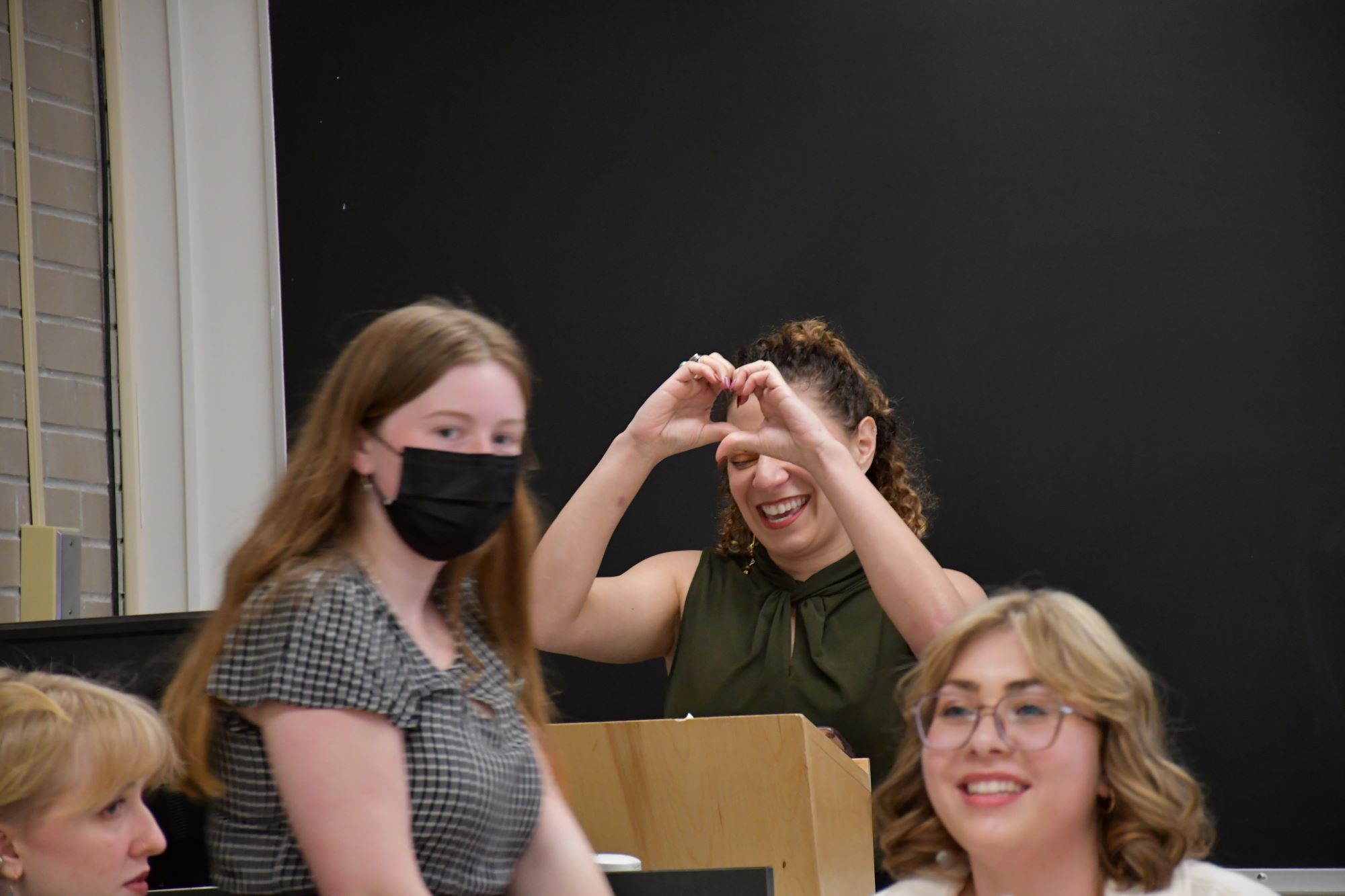 Salem making a heart shape with their hands while presenting